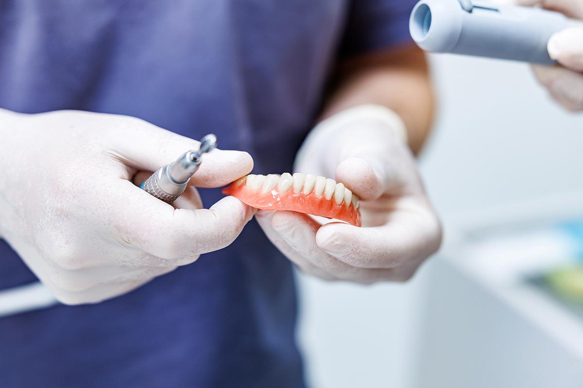 artdent-klickprothese-kosten-preisvergleich-oesterreich-ungarn-1 Dr. Artúr Varajti, Zahnarzt und Oralchirurg bei Artdent, hält eine Klickprothese in der Hand.
